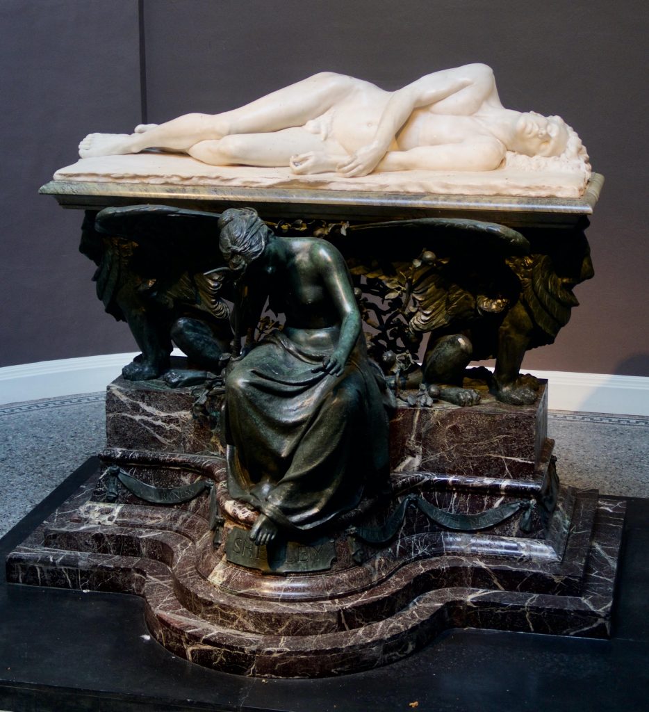 Image of a white marble statue of Percy Shelley's drowned body on a plinth.